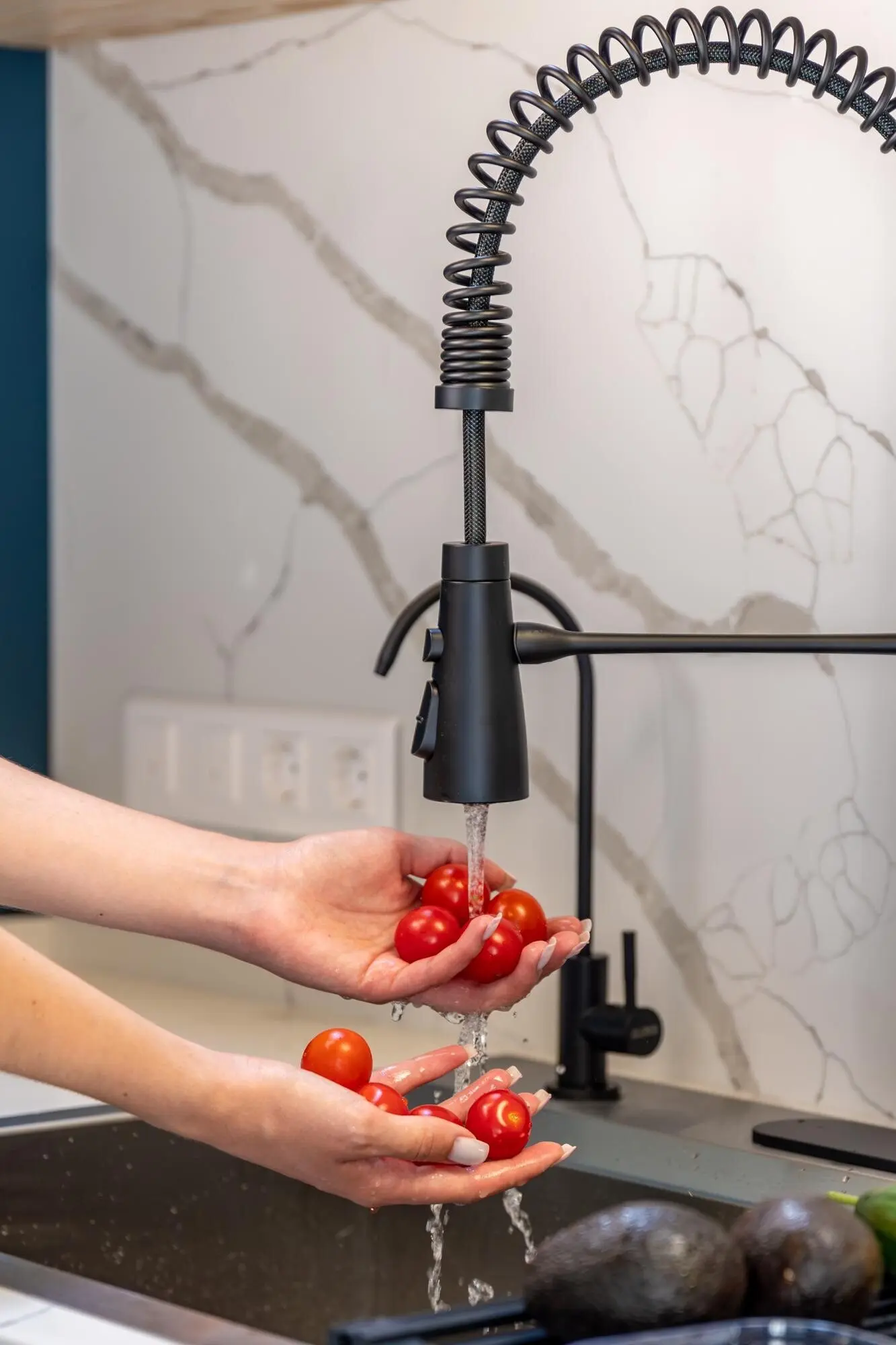 Weibliche Hände waschen Kirschtomaten unter dem Wasserhahn, saubere Vorbereitung.